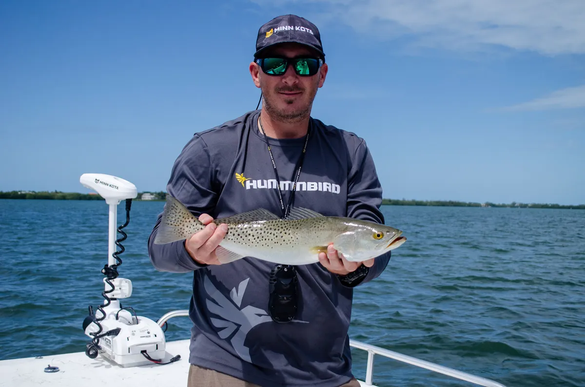 Angler holding a freshly caught fish on a boat